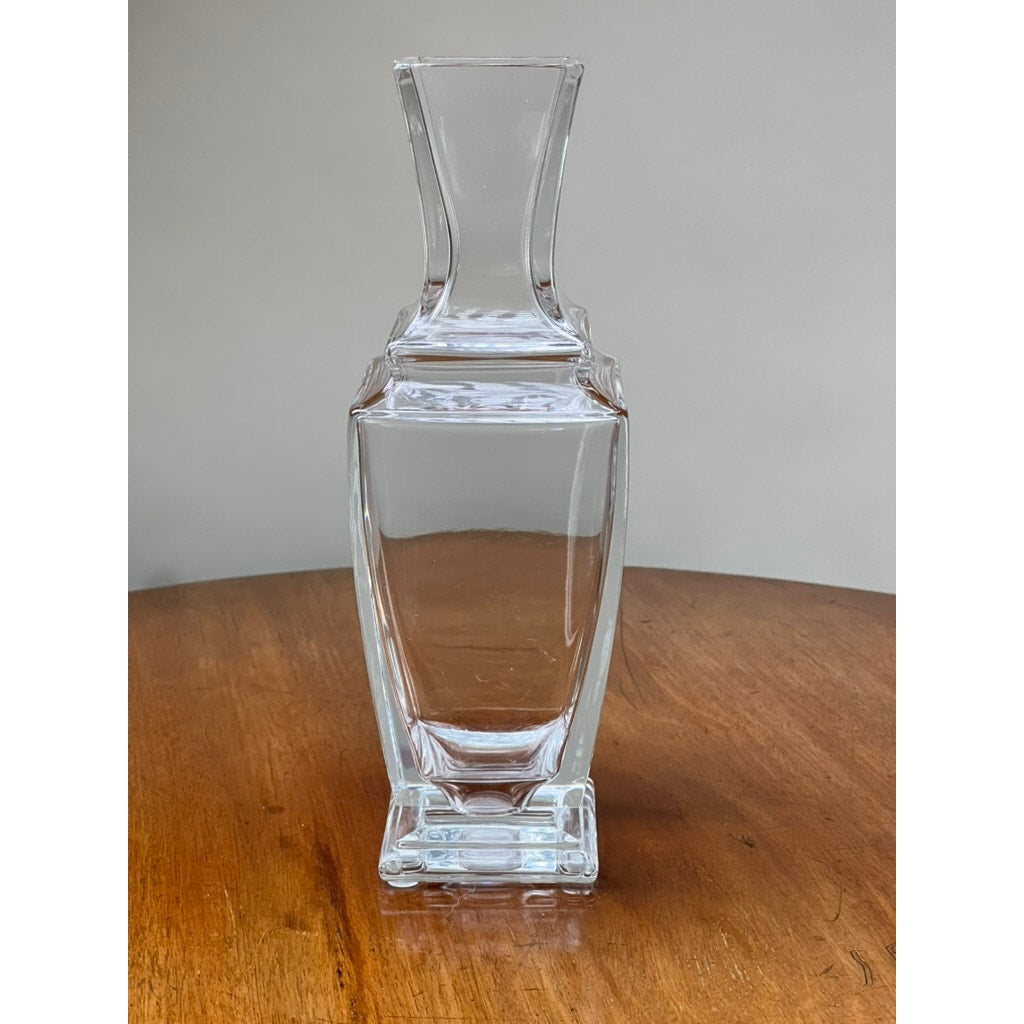 The Vintage Baccarat Crystal Pearl Vase by Baccarat, featuring elegant French-inspired design, sits on a wooden surface against a plain, light-colored background.