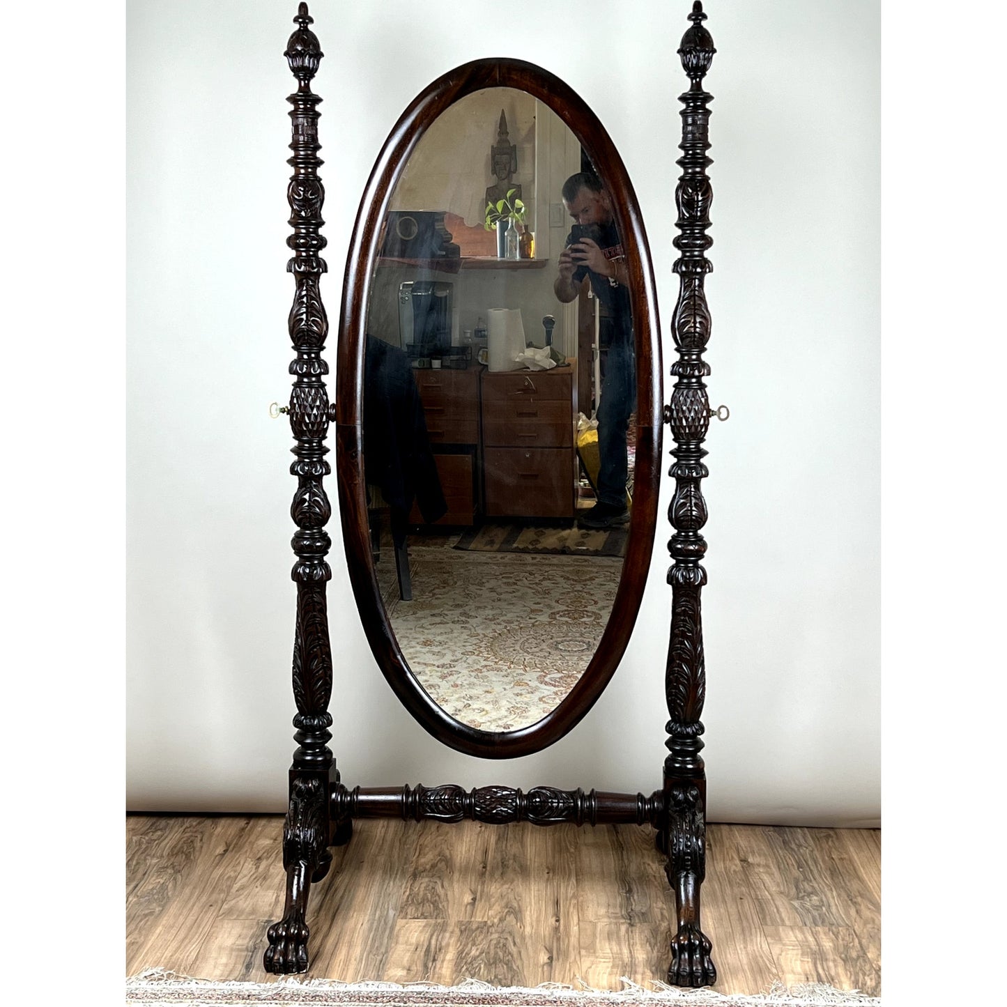 An Impressive Antique American Empire Acanthus and Barbola Rose Carved Cheval Mirror c. 1840 stands on a wooden floor; a person is seen in its reflection, photographing the room’s furniture and decor. Brand: None/Unknown.