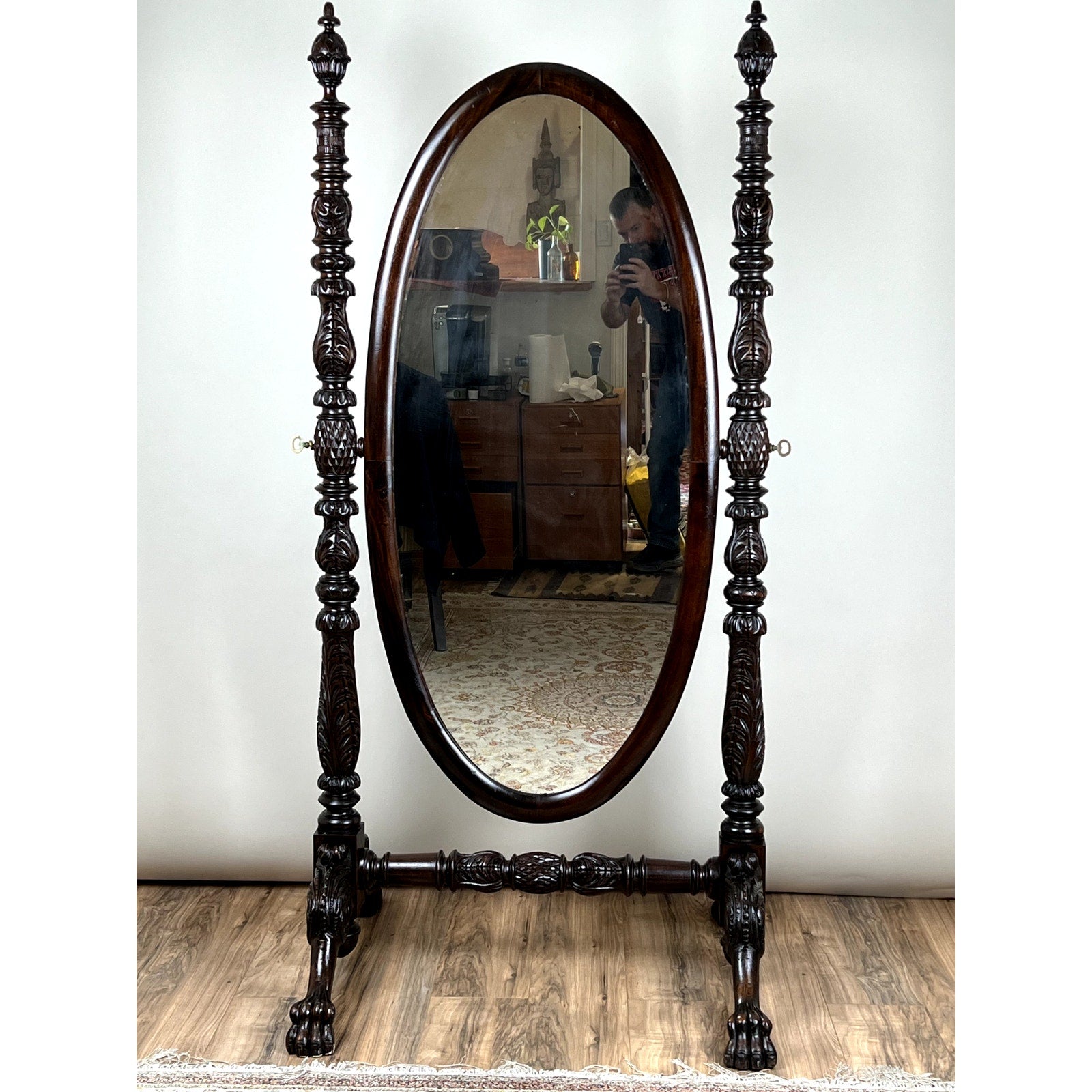 An Impressive Antique American Empire Acanthus and Barbola Rose Carved Cheval Mirror c. 1840 stands on a wooden floor; a person is seen in its reflection, photographing the room’s furniture and decor. Brand: None/Unknown.