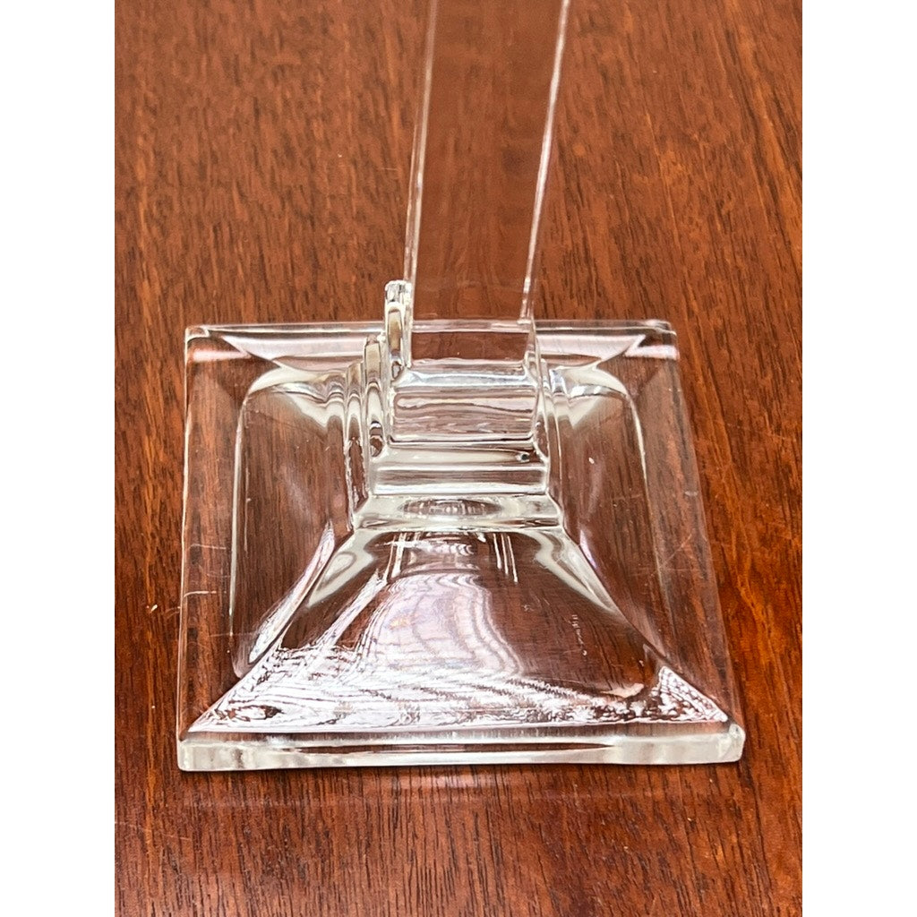 A vintage pair of Tiffany & Co. clear crystal candlesticks with smooth edges sit on a polished wooden surface, reflecting light for a shiny appearance reminiscent of classic Tiffany & Co. home decor.