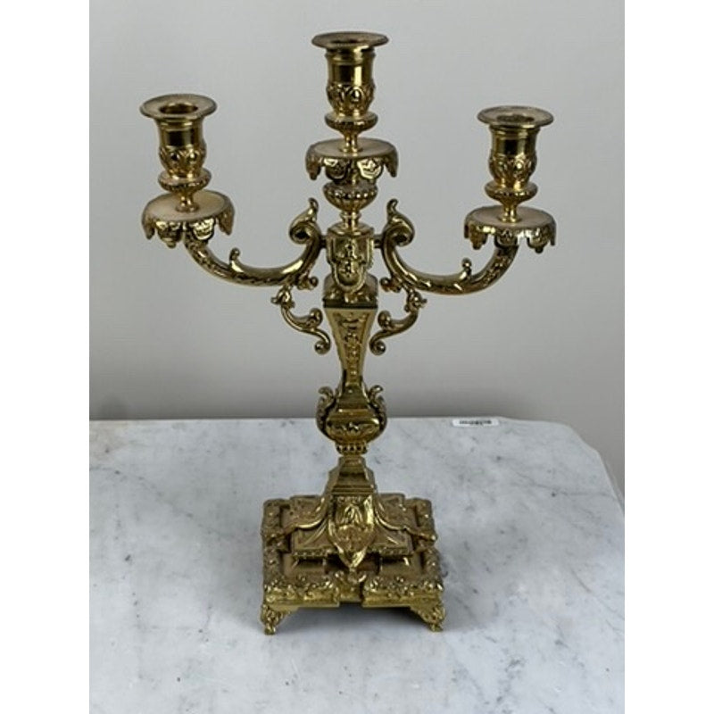 An antique pair of late 19th-century brass three-light candelabra with ornate scrollwork and decorative detailing stand on square bases, perfect for adding Victorian charm to your home décor. Brand: None/Unknown.