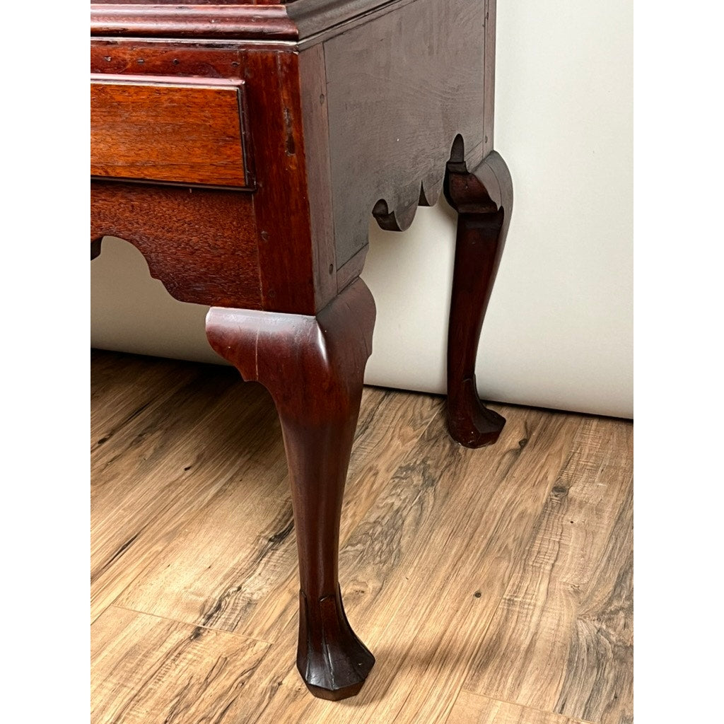 A close-up of the carved drake feet and curved legs of an Antique Queen Anne Walnut Chest on Frame, probably Irish from the late 18th century, set on a wooden floor against a plain light-colored wall.