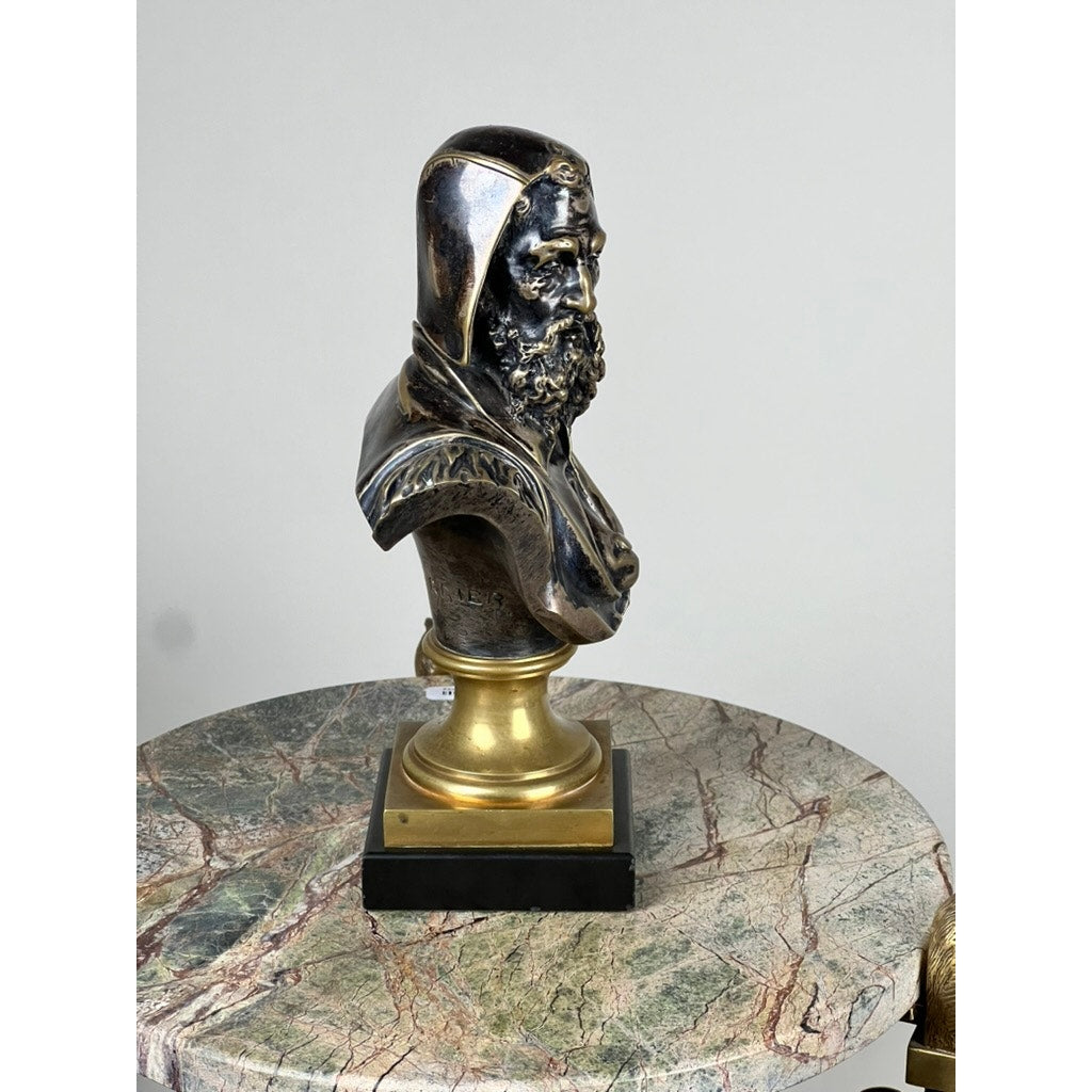 A patinated bronze sculpture of Michelangelo by Albert-Ernest Carrier-Belleuse (modeled before 1883, Paris) is displayed on a round, marble-topped table against a plain, light-colored background.