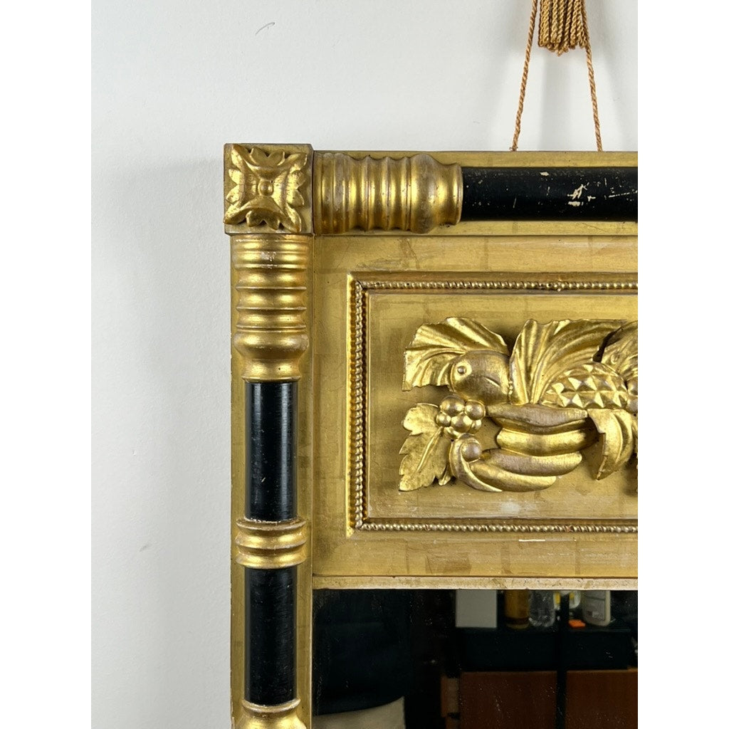Close-up of an Antique Federal Period Giltwood Mirror with Rosette Corners and Cornucopia, c. 1830. This detailed mirror features black vertical accents, ornate giltwood, and hangs from a rope against a white wall. Brand: Unknown.