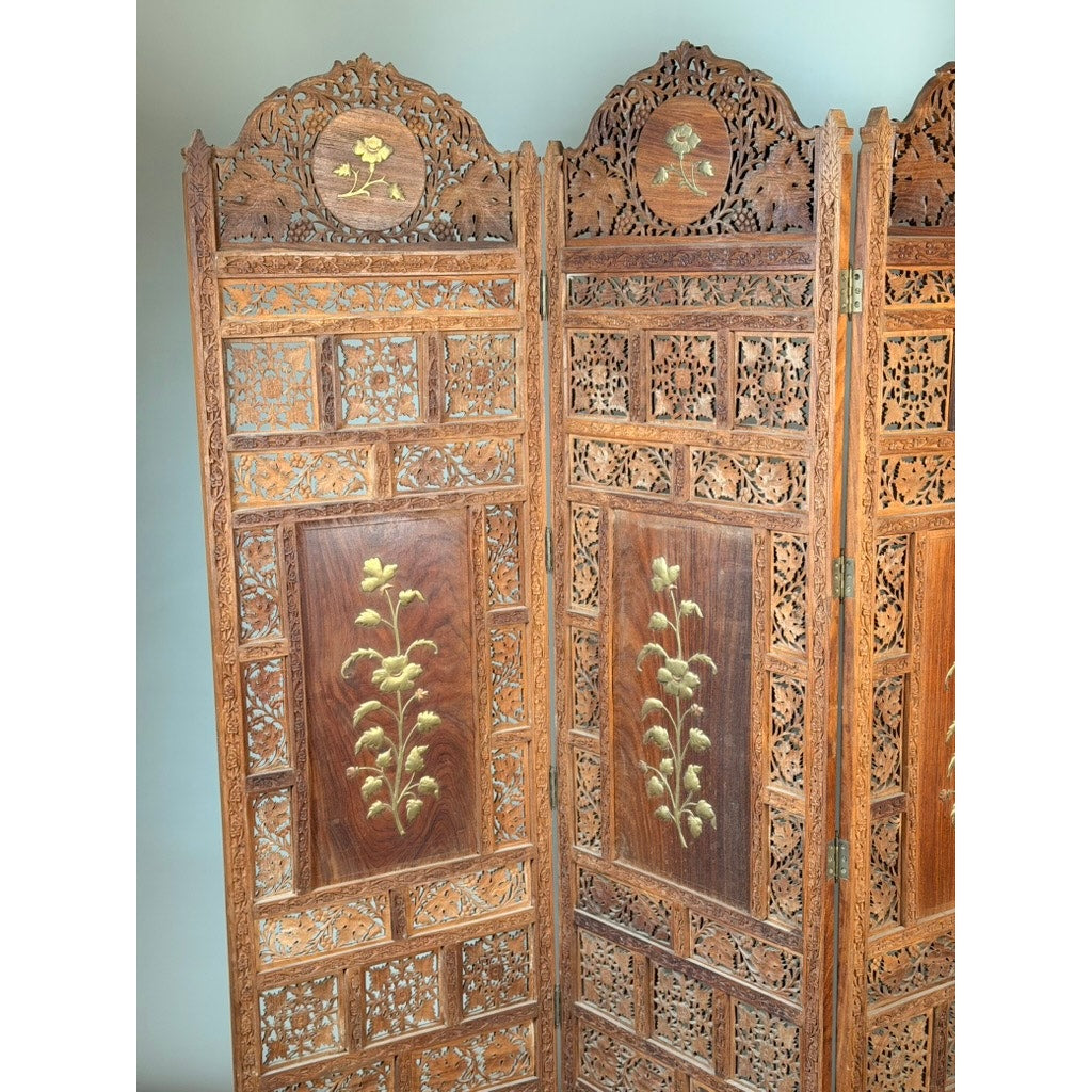 Discover the elegance of the Early 20th Century Anglo-Indian Carved Teak Four-Panel Screen with Applied Brass Floral Decoration from Pearl City Antiques. This exquisite antique features dark teak panels adorned with intricate carvings and inlaid brass floral motifs, while the top showcases ornate openwork detailing and circular floral patterns set against a lighter background. A remarkable folding screen, it adds timeless sophistication to any refined living space.