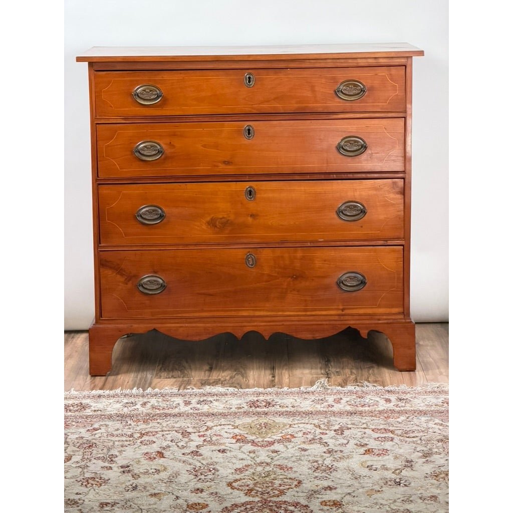 Pennsylvania Federal Cherry Four-Drawer Chest with Satinwood String Inlay, featuring brass oval pulls, keyhole escutcheons, and a scalloped base.
