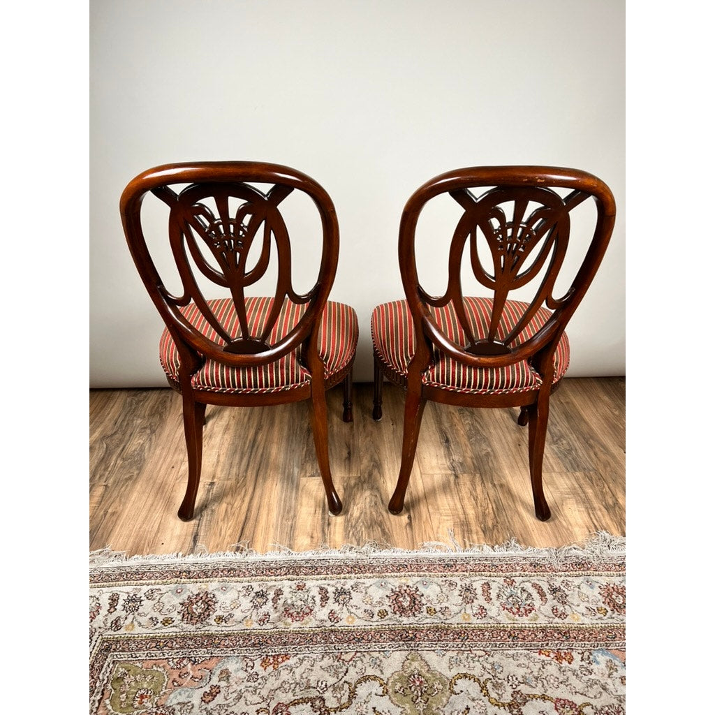 A vintage pair of Ardley Hall Wheel Back Side Chairs with red striped upholstery stand side by side on a wood floor, with a patterned rug partially visible in the foreground.
