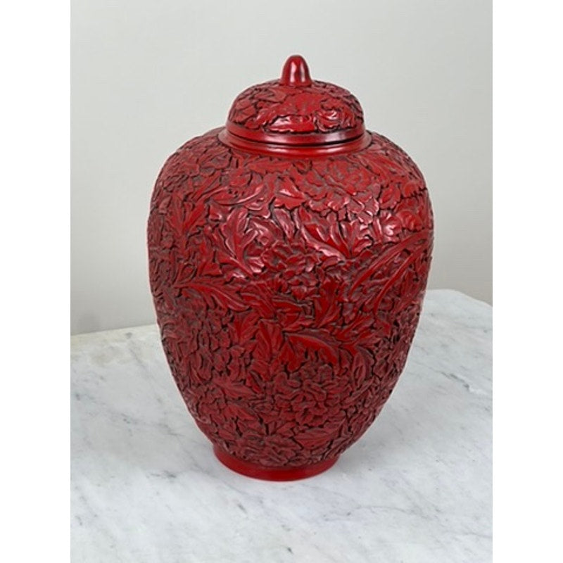 An Antique Chinese Hand-Carved Cinnabar Lacquered Lidded Jar, probably Qianlong, with intricate floral patterns is displayed on a white marble surface against a plain light background.
