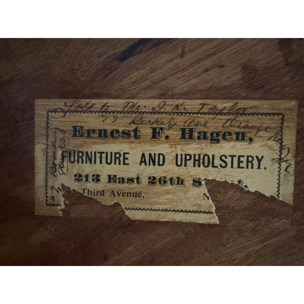 A rectangular furniture label for Ernest F. Hagen, Furniture and Upholstery, with a handwritten address and owner name, partially torn at the bottom of a New York Classical Revival Carved Mahogany Double-Pedestal Library Table.