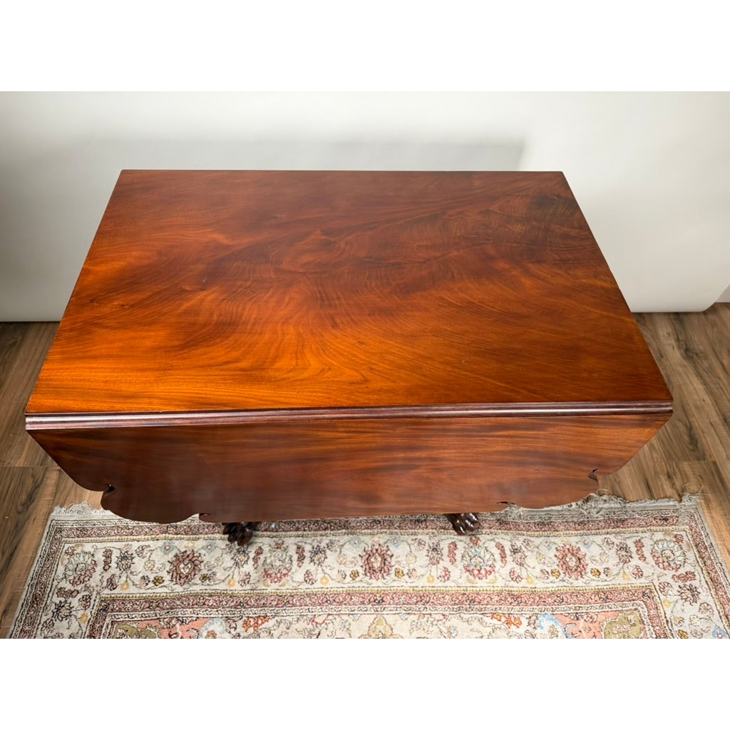 High-angle view of an American Classical Carved Mahogany Drop-Leaf Breakfast Table, c. 1825–1840 Possibly New York or Philadelphia, with rectangular mahogany leaves, carved pedestal feet, and a patterned rug underneath.