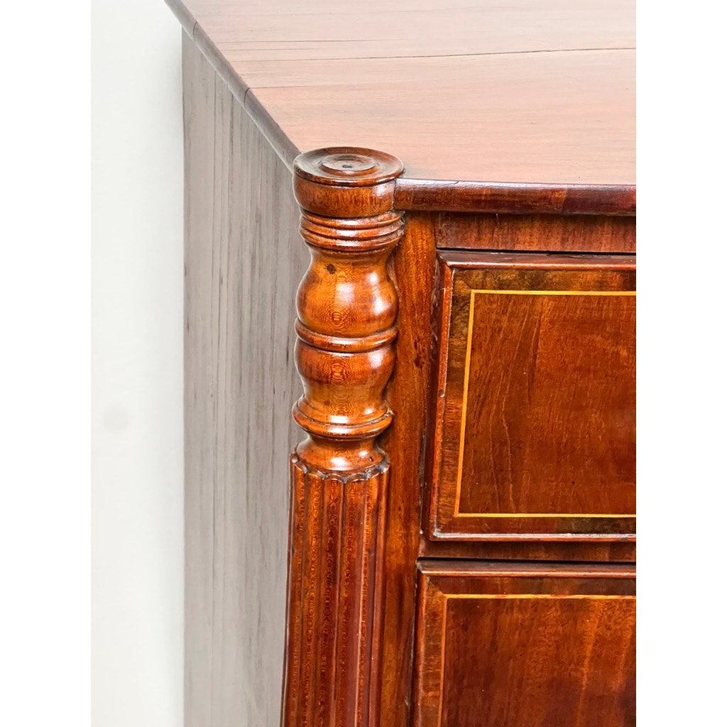 Close-up of a polished corner on the Antique Sheraton Mahogany Bowfront Chest (Early 19th Century), highlighting an ornate rounded column and contrasting inlaid trim reminiscent of sophisticated period design.