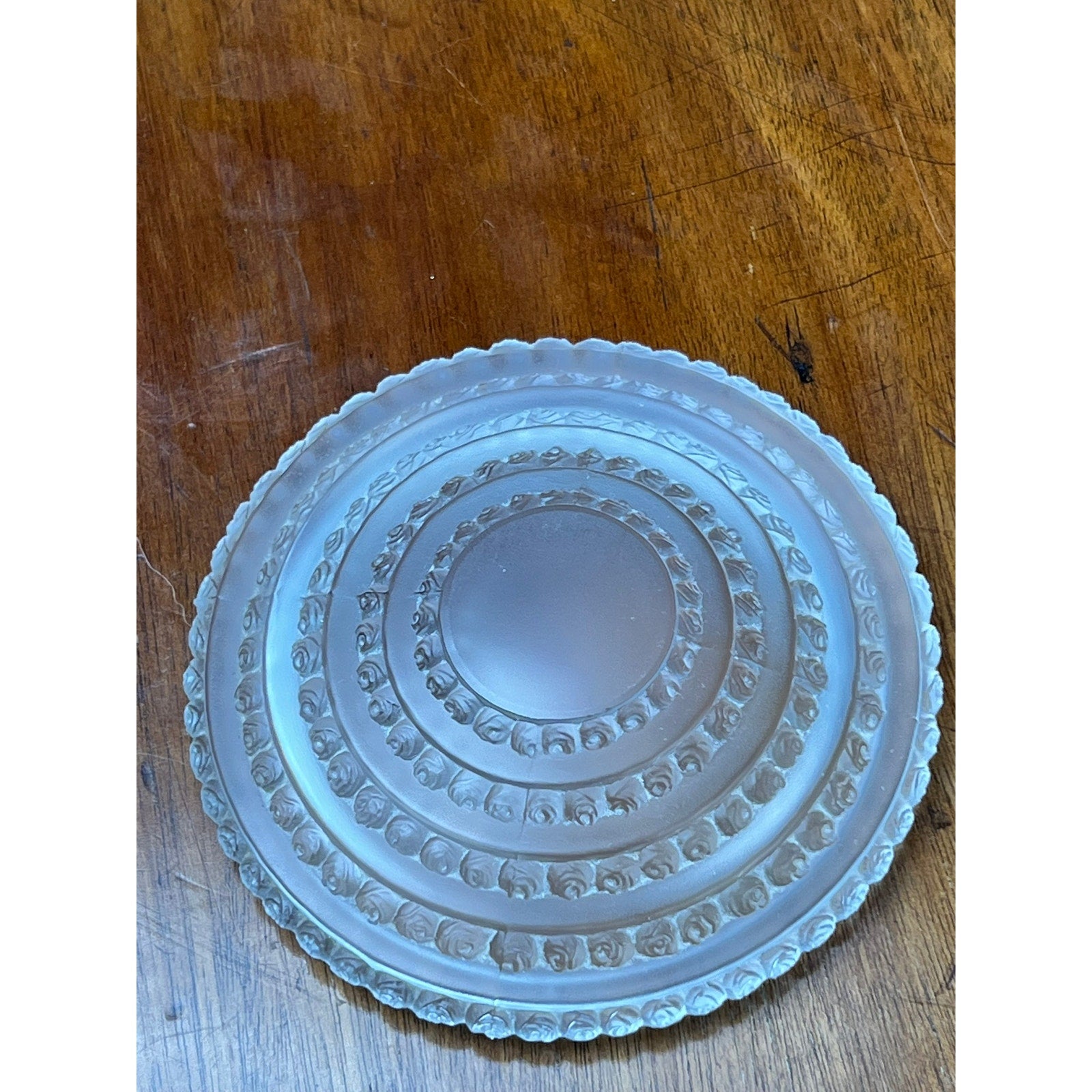 A Vintage Lalique Crystal Enfants Box by Lalique is displayed on a wooden surface, featuring ornate circular designs and a scalloped edge reminiscent of French art glass.