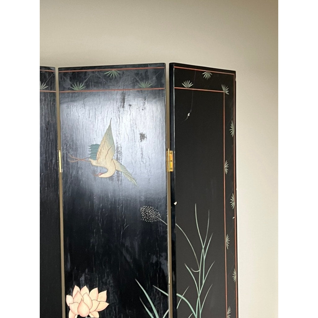 A Vintage Asian Black Lacquer Coromandel Room Screen with painted cranes, lotus flowers, reeds, and pine needles stands against a light wall, reflecting the elegance of Chinese decorative art.
