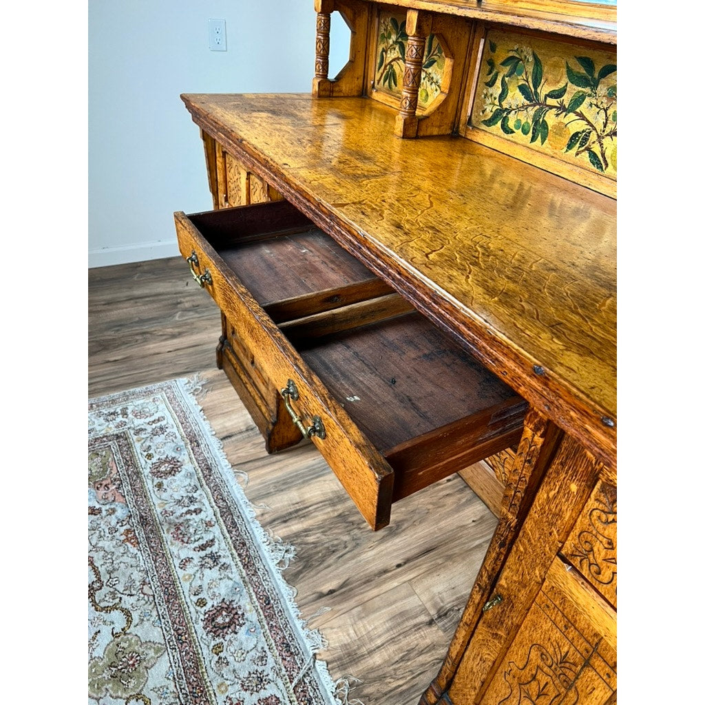 Antique Victorian Aesthetic Movement oak desk in original finish (late 19th century), with ornate carvings and floral panel, open drawer revealing compartments; displayed on hardwood floor beside a patterned rug. Brand: Unknown.
