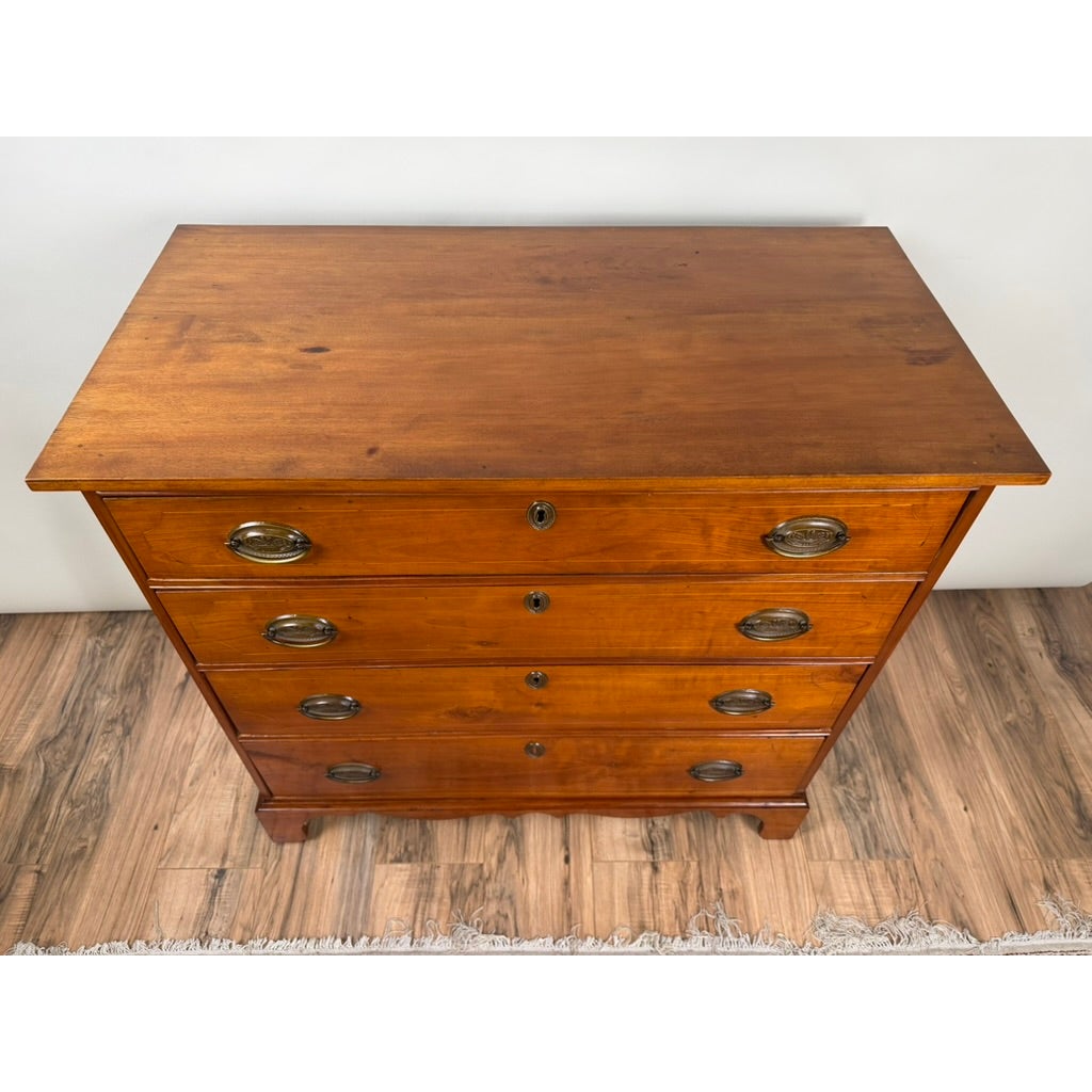 High-angle view of a Pennsylvania Federal Cherry Four-Drawer Chest with Satinwood String Inlay, featuring four drawers with brass pulls and keyhole escutcheons in the Federal style.