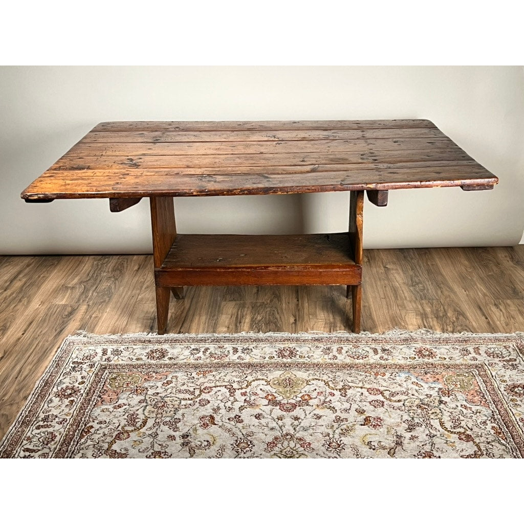 An Antique Country Pine Hutch Table with Six Plank Top (c. 18th Century) stands on a wooden floor beside a light floral area rug; the background features a plain, light-colored wall.