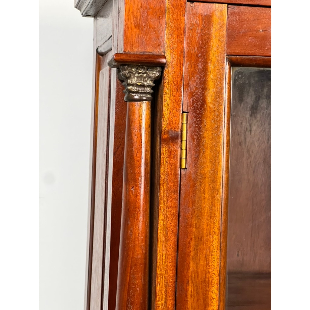 Close-up of a Vintage Victorian Style Glass Door Mahogany Bookcase featuring a decorative carved column, metallic-colored capital, brass hinge, and polished reddish-brown finish. Brand: Unknown.