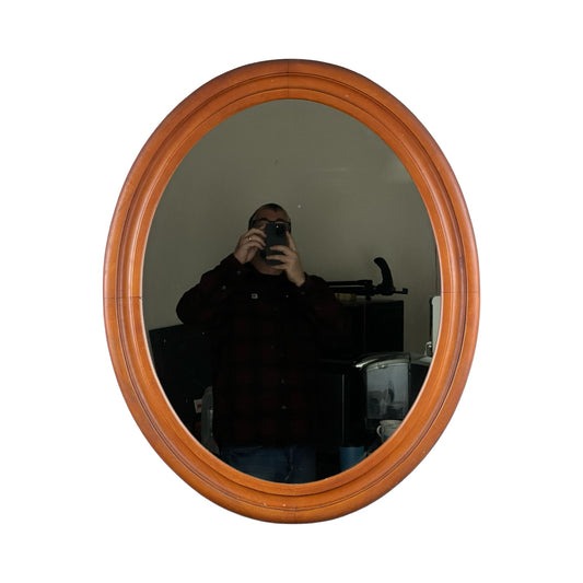 A person is taking a selfie in a Vintage Oval Maple Wall Mirror, with various furniture and objects visible in the background. Brand: None/Unknown.