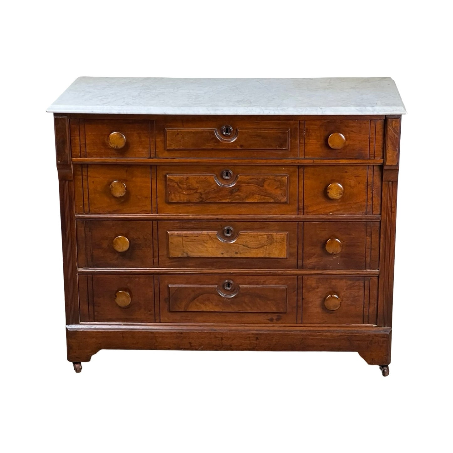An Antique Victorian Marble Top Four Drawer Chest c. 1910 featuring a white marble top, round brass knobs, and small caster wheels—a charming vintage piece. Brand: Unknown.