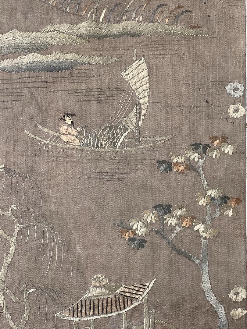 The Antique Chinese Embroidered Panel on Silk c. Late 19th Century by Pearl City Antiques features a person in a sailboat near trees and a thatched-roof, crafted in muted earth tones—echoing the elegance of historic textile art.