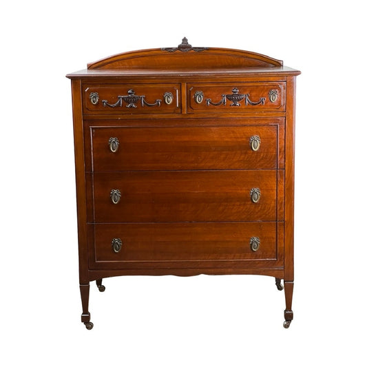 This Antique Depression Era Mahogany Two Over Three Chest of Drawers (c. 1930s) features four drawers with ornate metal handles, decorative carvings, slender legs with small wheels, and a decorative backboard. Brand unknown.