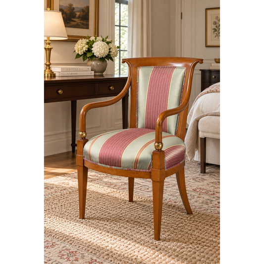 William Switzer French Empire Style Beechwood Armchair by William Switzer: This beechwood armchair, designed in the French Empire style, features gracefully curved arms and legs and is upholstered in striped red and green fabric. Positioned on a textured rug in a traditional, well-lit room near a desk, lamp, and bed.