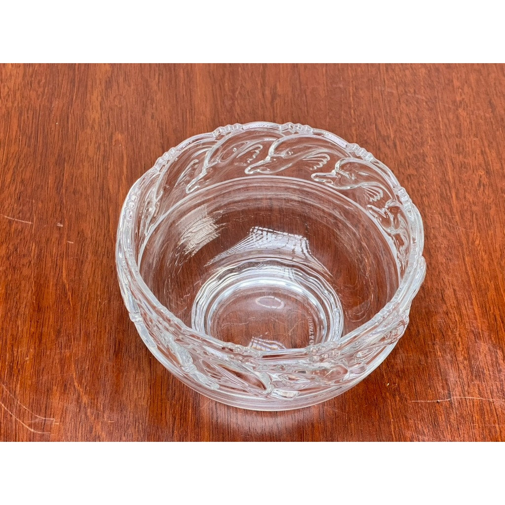 A Vintage Tiffany & Co. Mid-Century Modern Crystal Dolphin Pattern Footed Bowl sits on a polished wooden surface.