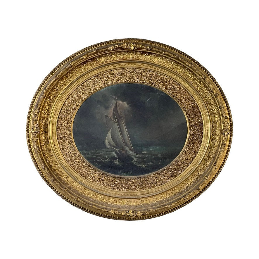 The Antique Oval “Storm Tossed Ship” Oil on Board Painting c. Late 19th Century features a sailboat braving stormy, dark waters at night, set in an ornate gold frame with swirling clouds and waves for a dramatic maritime scene.