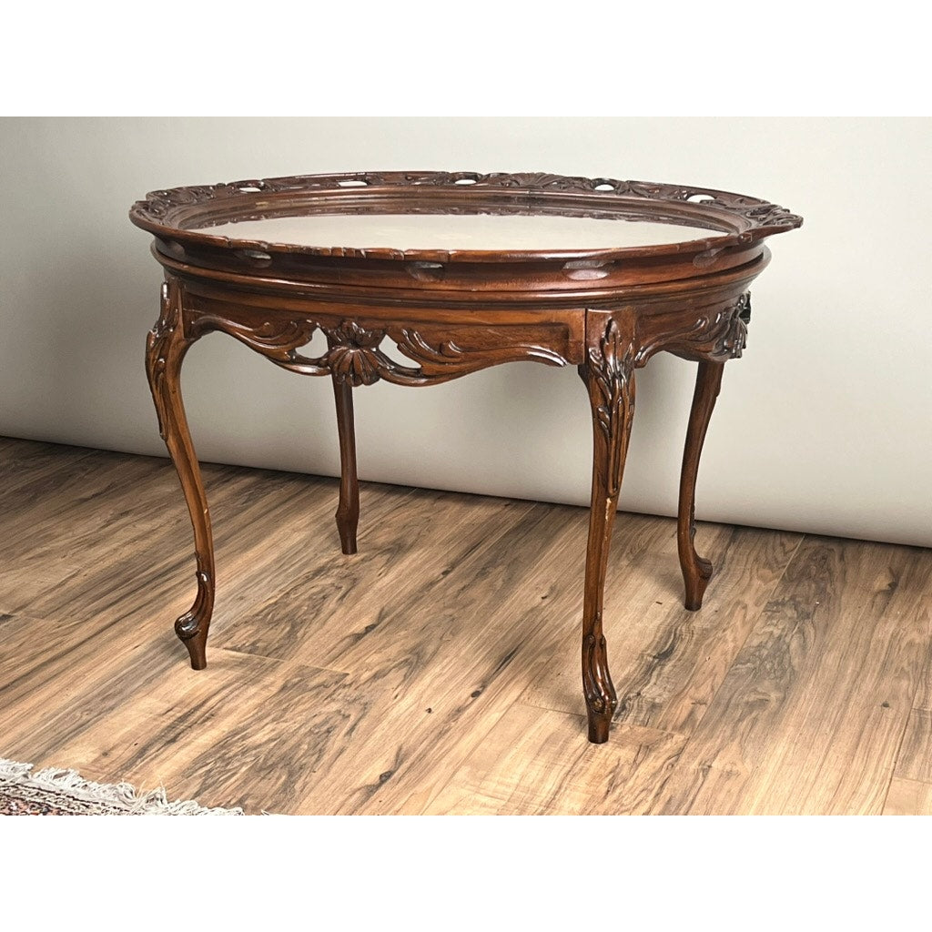 A vintage Louis XVI style butlers table with a removable glass tray stands on a wooden floor against a plain light-colored wall. Brand is unknown.