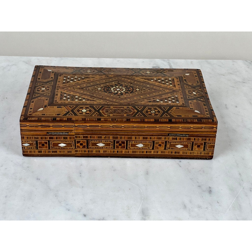 An Antique Persian (likely Syrian) Khatam Wood Inlaid Jewelry Box, early 20th century, features intricate brown, tan, and white geometric designs— an exquisite example of Middle Eastern decorative woodworking displayed on white marble.