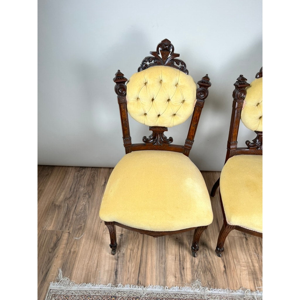 A Fine Antique Pair of Renaissance Revival Walnut Side Chairs, attributed to John Jelliff (Newark, c. 1880), features ornate carved details and yellow tufted upholstery, shown on a wooden floor with part of the matching chair visible.