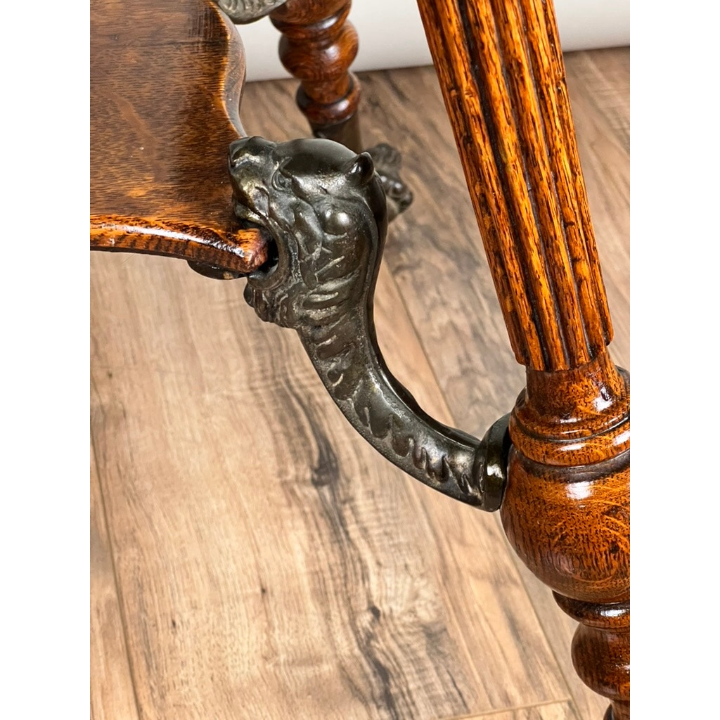 Close-up of an Antique Victorian Oak Lamp Stand (late 19th c.) featuring ornately carved legs and decorative bronze lion’s head mountings, shown against a wood floor background. Brand: Unknown.