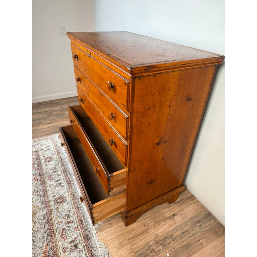 A Late 18th Century New England Pine Two-Drawer Blanket Chest, c. 1780–1810 by Pearl City Antiques stands on a wood floor beside a patterned rug and a white wall, evoking the charm of early American country furniture.