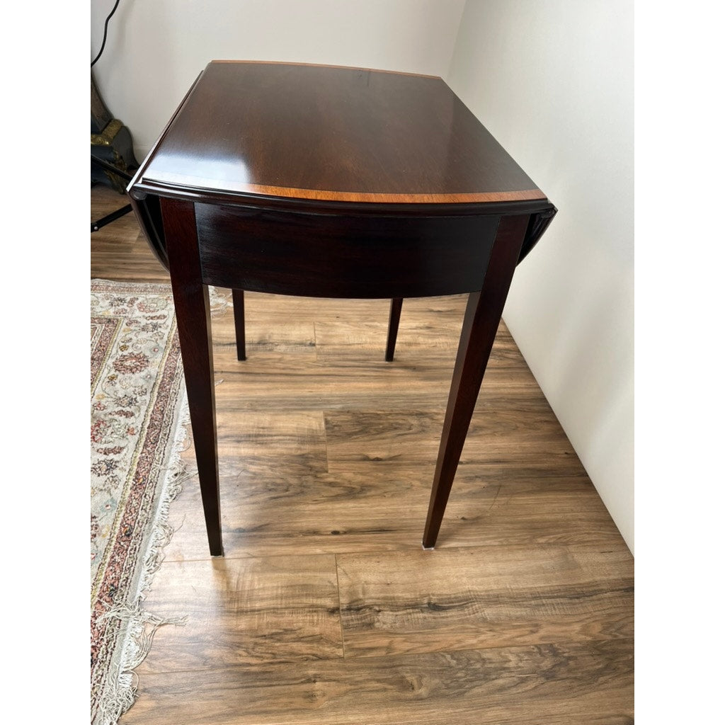 The Vintage Federal Style Edge Banded Mahogany End Table by Stickley features tapered legs and a drop-leaf design, adding classic charm and versatility to any space. Its compact size makes it perfect for placement near a rug or white wall.