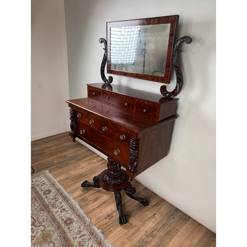 American Classical Carved Mahogany Dressing Table with Original Mirror, probably New York, c. 1825–1835, featuring a rectangular mirror, three small drawers, two large drawers, and a central pedestal base with carved feet.