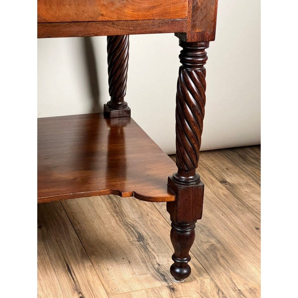Close-up of an Antique Federal Mahogany Two Drawer Work Stand c. 1820, showing a twisted carved leg near the lower shelf, set on a light wood floor with a plain background. Features include lion’s head pulls; maker unknown.