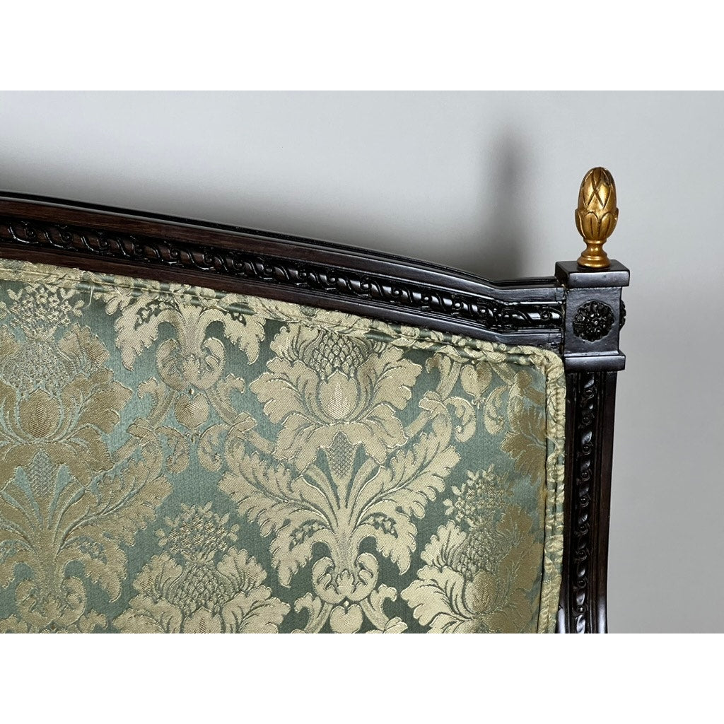 Close-up of a Vintage Louis XVI Style Settee in green damask upholstery, featuring ornate carved wooden trim and a decorative gold finial on the corner, set against a plain background. Brand: Unknown.