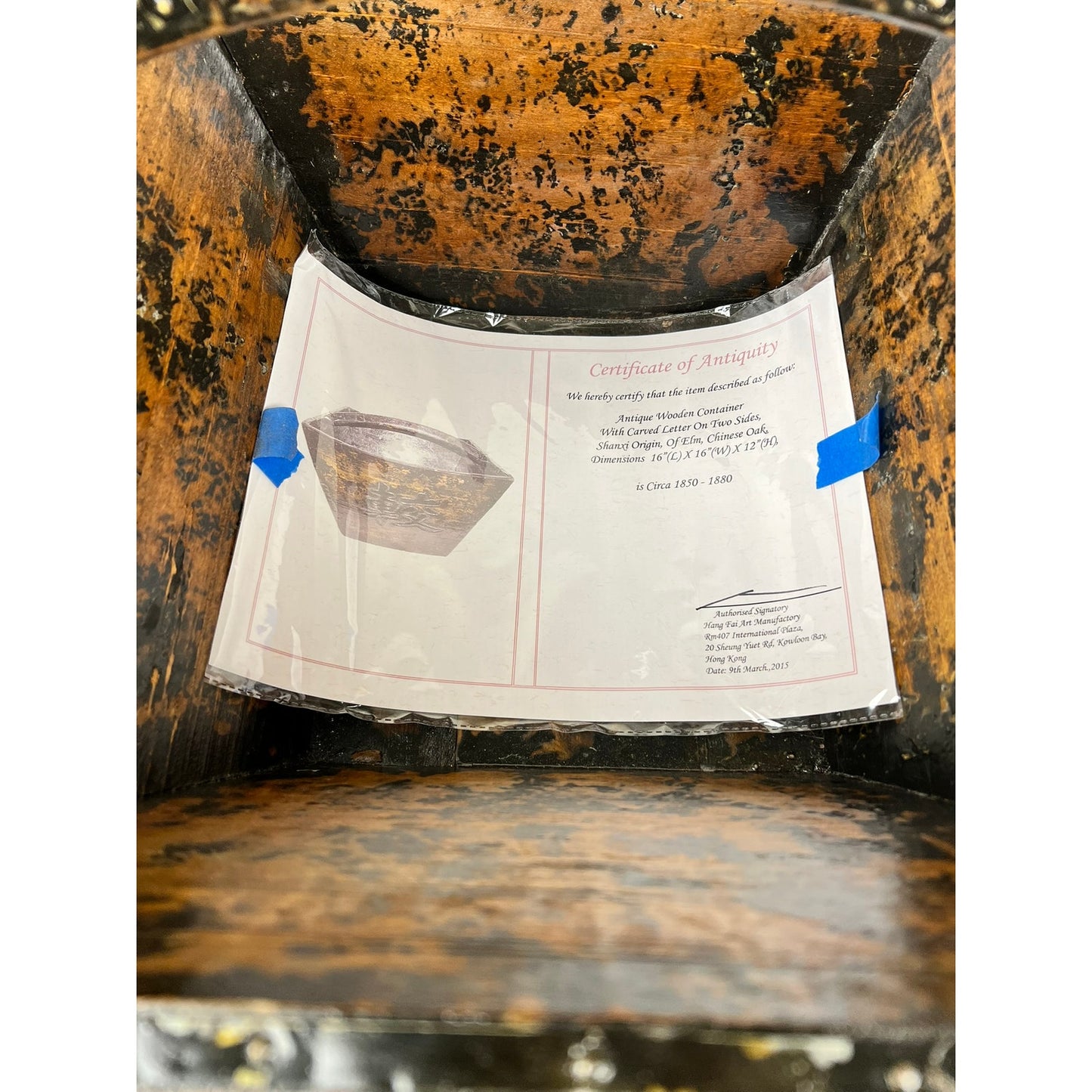 A laminated certificate, featuring a photo and authenticity details for an Antique Chinese Elm Dou Rice Measure, likely from Shanxi c. mid-19th century, is taped inside a worn brown and black antique wooden box. Brand: None/Unknown.