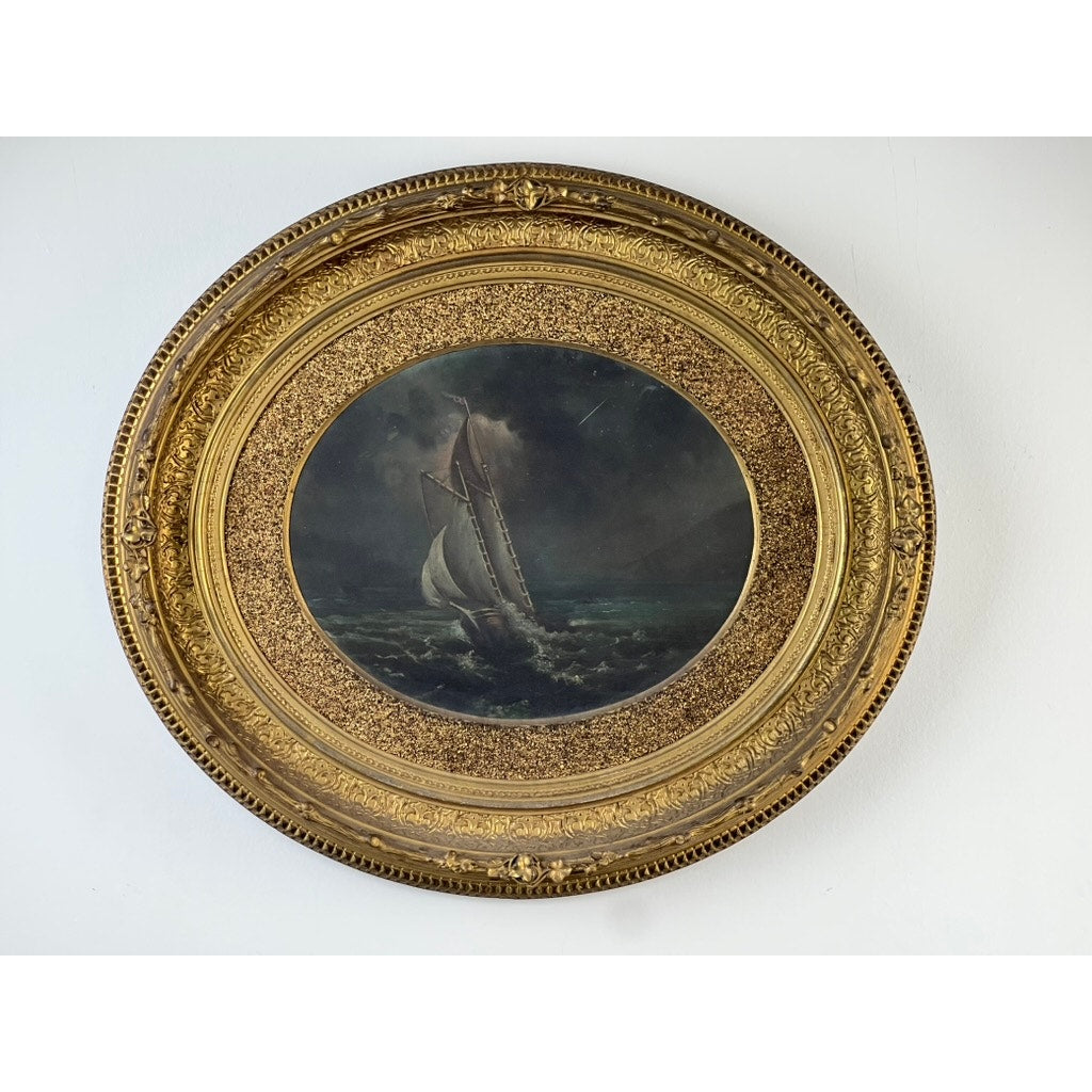 Antique Oval “Storm Tossed Ship” Oil on Board Painting c. Late 19th Century, in an ornate round gold frame with intricate patterns, is displayed against a plain white wall. Brand: None/Unknown.