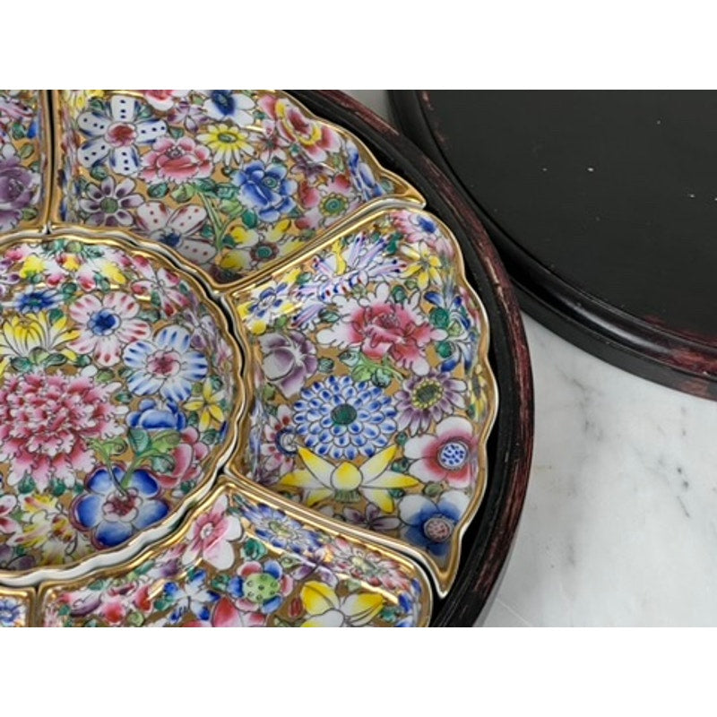 A close-up of a Vintage Chinese Canton Sweet Meat Set with Case, c. Early 20th Century, showing its segmented famille rose porcelain dish with vibrant floral patterns and gold accents on a dark round tray atop white marble.