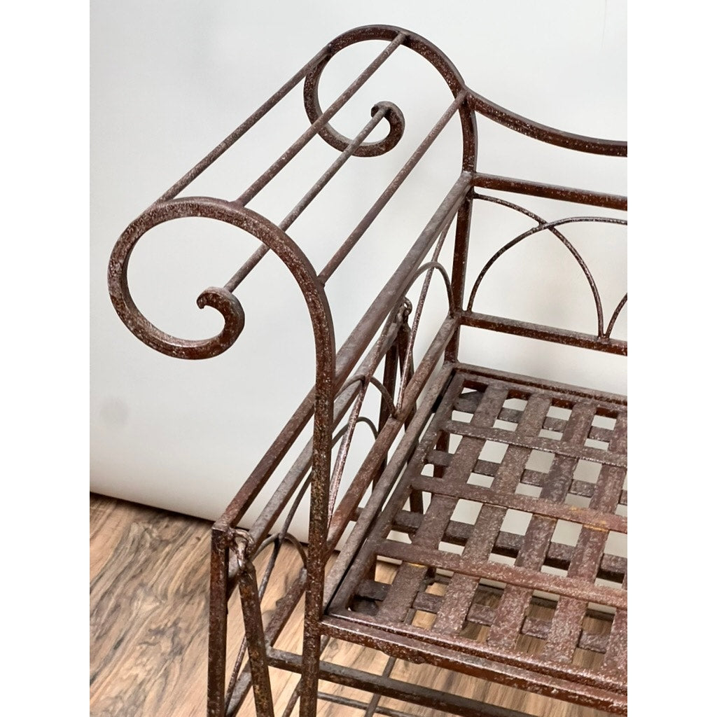 A close-up of a Vintage Regency Style Wrought Iron Porch Glider with a brown, rusty finish. The armrest has a curled design, and the seat features a lattice pattern—ideal for adding vintage charm to any outdoor space. Brand: Unknown.