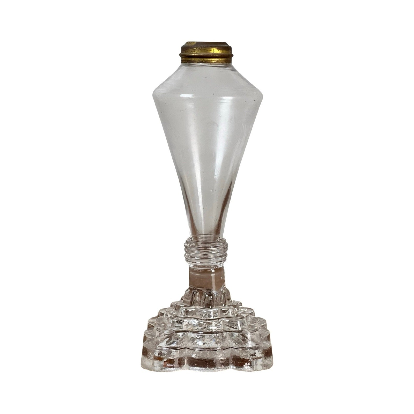An attributed Boston & Sandwich pressed glass boudoir fluid lamp, circa 1850, crafted in clear glass with a brass top, featuring a geometric stepped base and a tall, tapered body—evoking the style of Victorian-era pressed glass lamps.