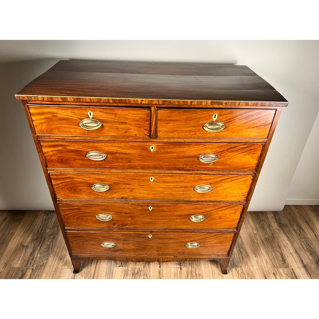 An Antique George III Two Over Four Chest with French Feet, c. Early 19th Century, crafted in mahogany and featuring six drawers, brass handles, and keyholes, sits on a hardwood floor against a plain light-colored wall. Brand: Unknown.
