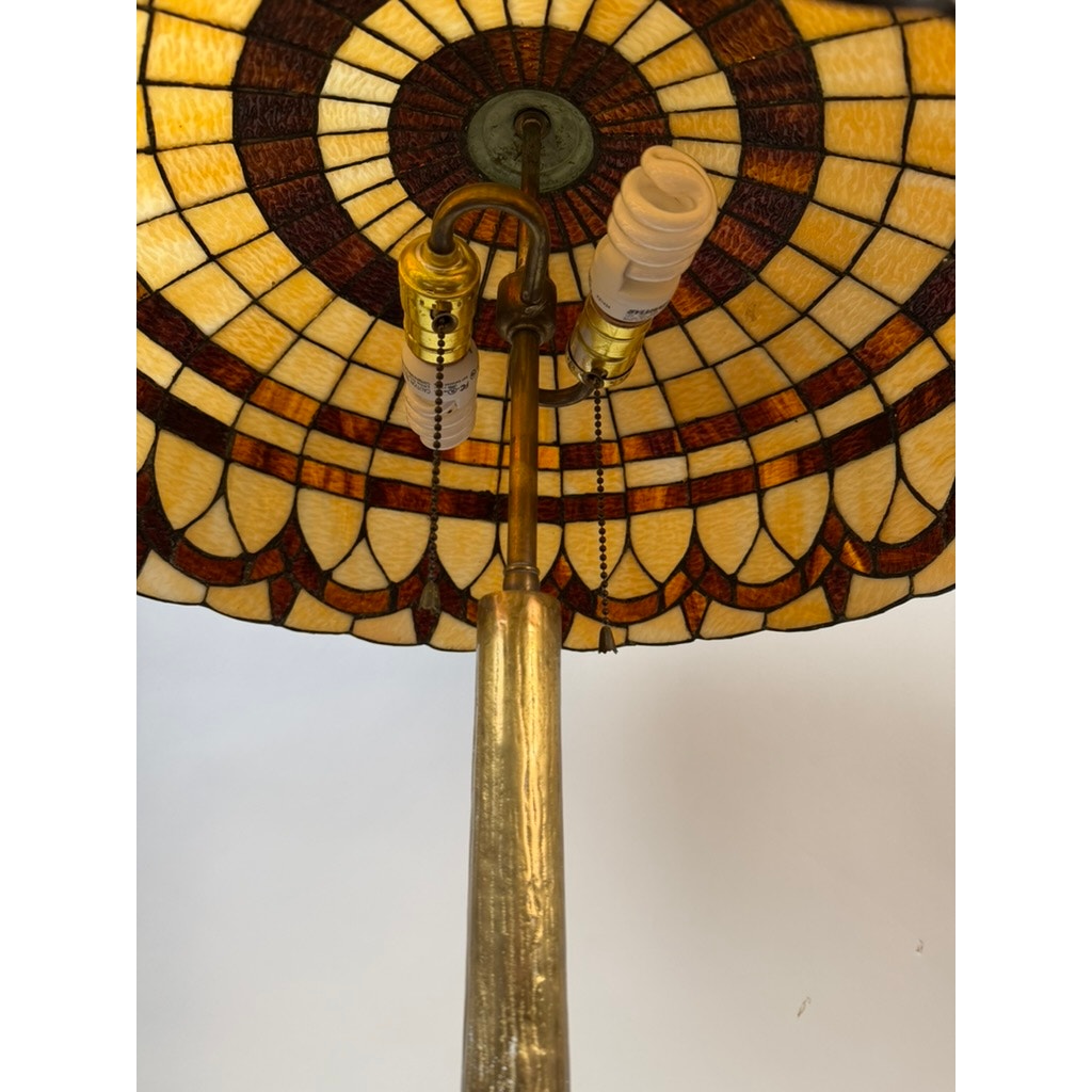 Close-up of the underside of the Vintage Tiffany Revival Leaded Stained Glass Table Lamp by Pearl City Antiques, showing two light sockets—one fitted with a compact fluorescent bulb and pull chain—attached to its cast brass tree-form base.