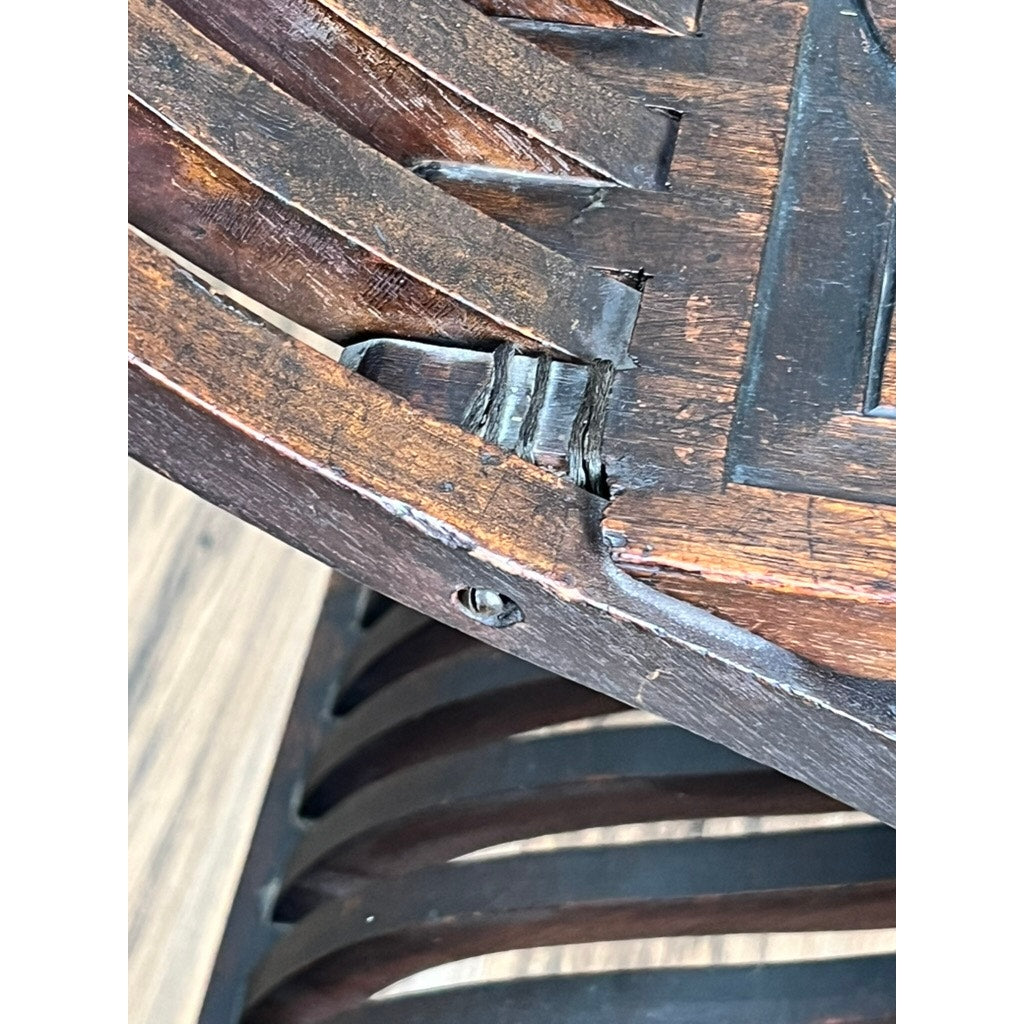 Close-up of an Antique Italian Renaissance Walnut Savonarola Chair (late 19th c.) shows a visible crack and damaged seat joint. The dark finish, worn to reveal lighter wood, highlights its rich history and aged character. Brand: Unknown.