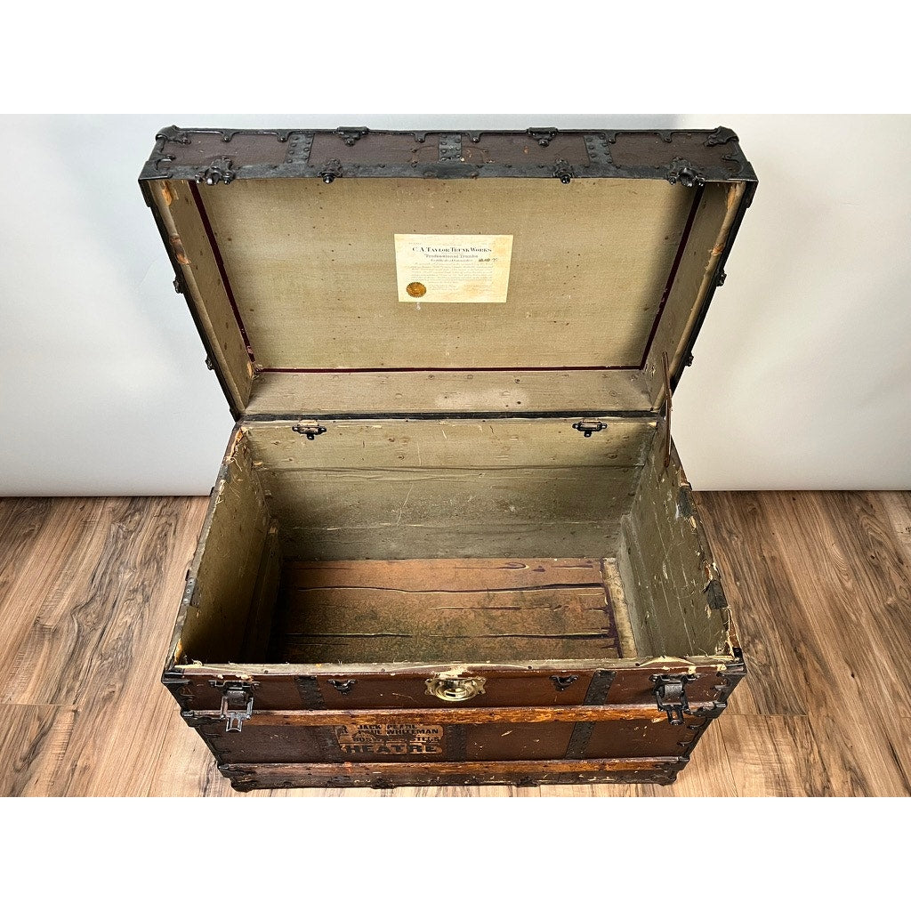A vintage CA Taylor Touring Trunk of John B. Cordaro, reed player for the Paul Whiteman Orchestra (c. 1930s), with metal reinforcements and a fabric-lined lid, sits open on a wooden floor, its label recalling classic big band tours.