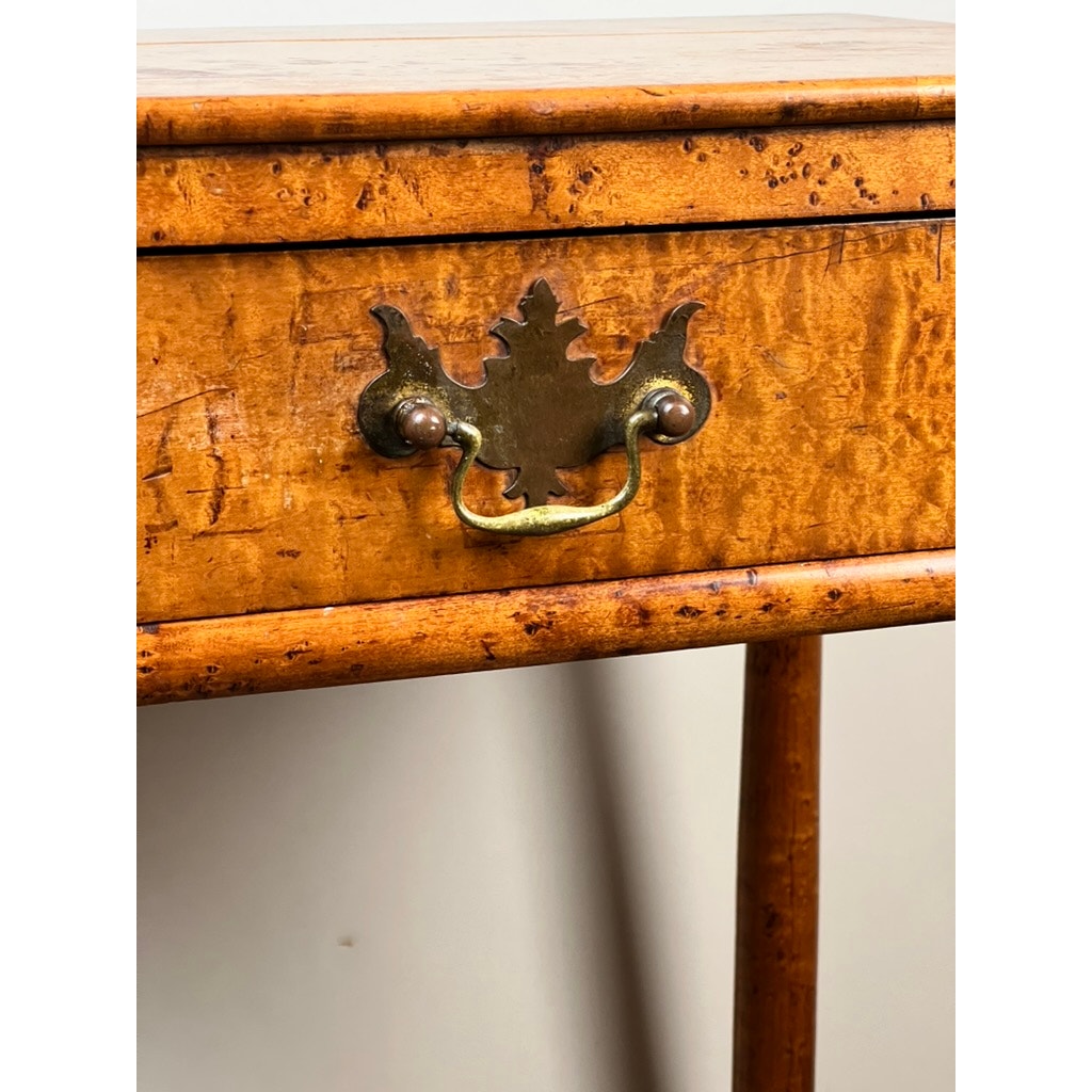 Close-up of an Antique Sheraton Birdseye Maple One Drawer Stand (c. Early 19th Century) showing a decorative brass handle, detailed escutcheon, and rich wood grain with natural imperfections against a plain background. Brand unknown.