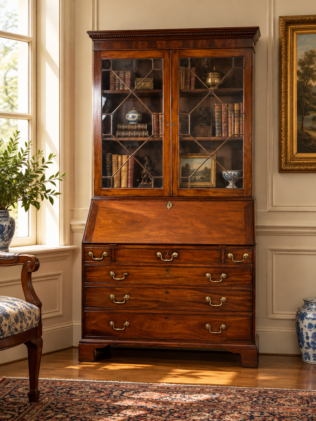 Antique George III Secretary with Bookcase c. Late 18th Century by Pearl City Antiques: a mahogany desk with a glass-fronted bookcase, brass pulls, and interior shelves filled with books and small decorative objects.