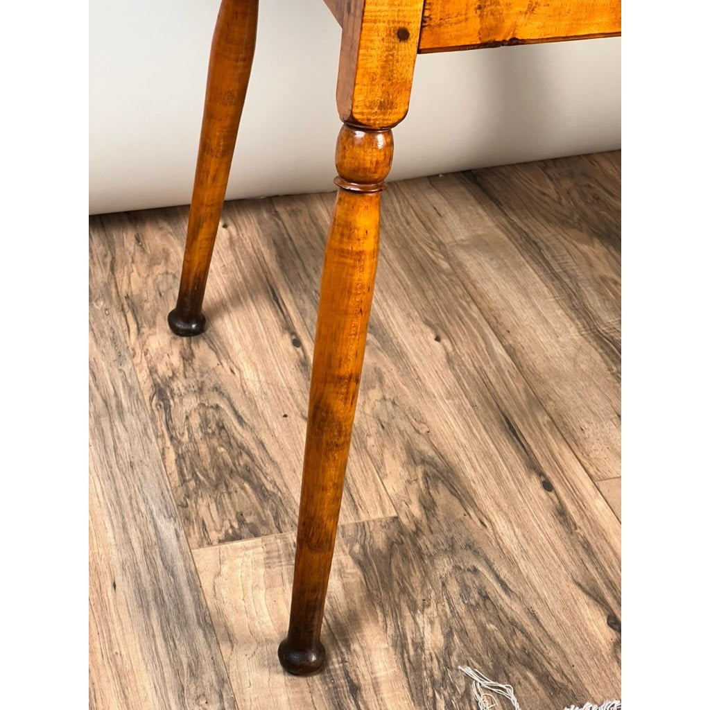 Close-up of two turned legs from an Antique American Queen Anne Maple Tavern Table, New England, Circa 1760–1790, showing a polished finish and darker feet on a light brown wood-patterned floor.
