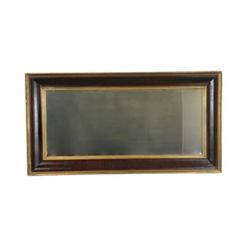 An Antique American Empire parcel gilt flame mahogany ogee wall mirror (mid-19th century) is displayed against a plain white background, featuring a rectangular frame with dark wood and gold accents.